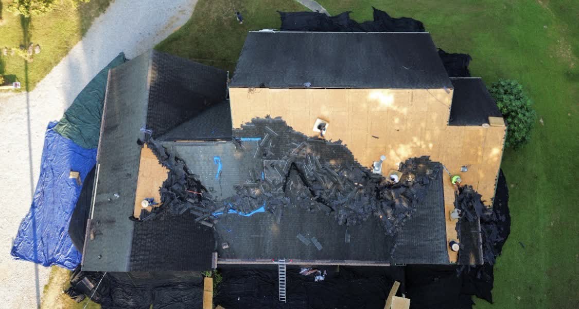 Drone view of an active tear-off — old shingles being stripped