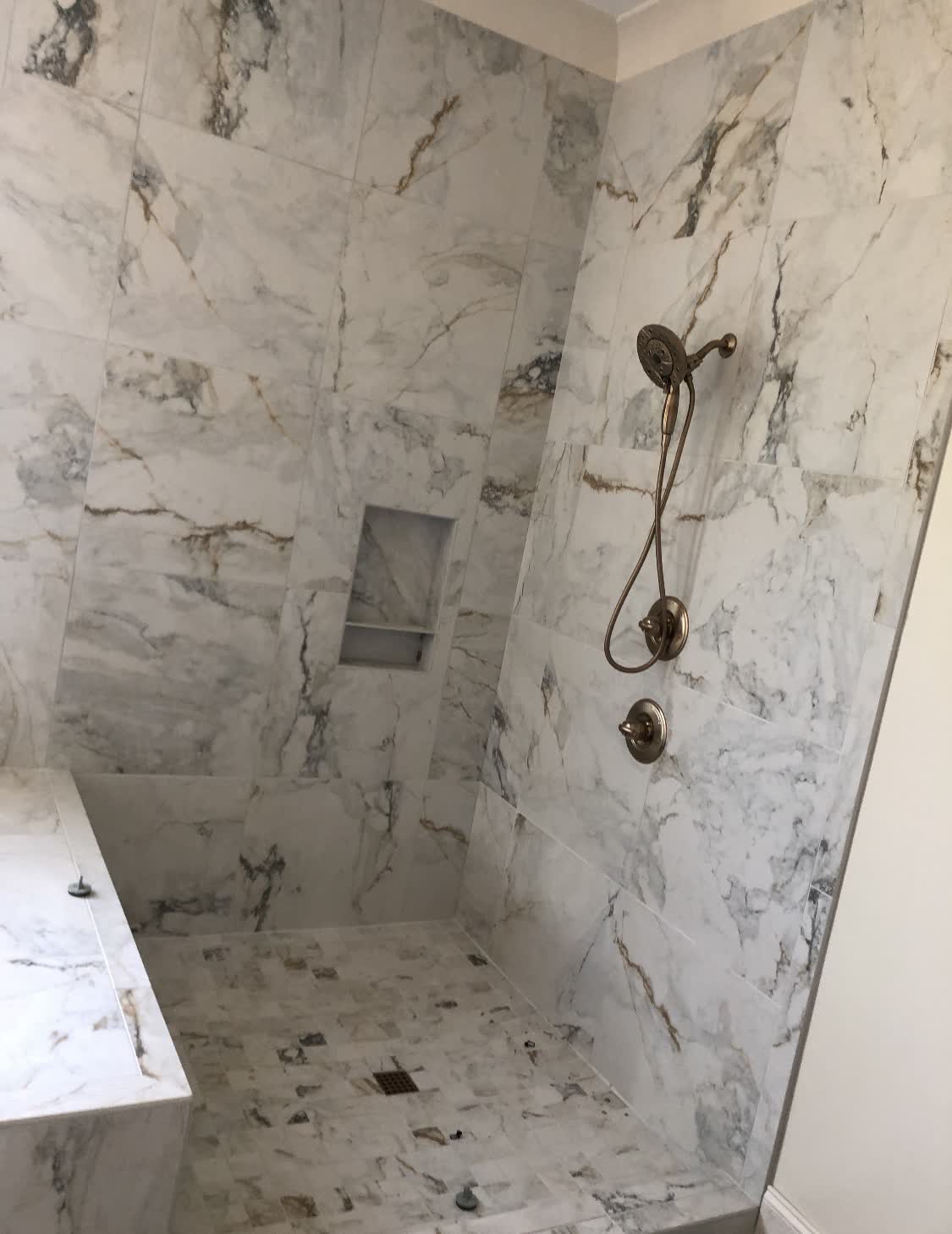 White marble shower with bronze fixtures