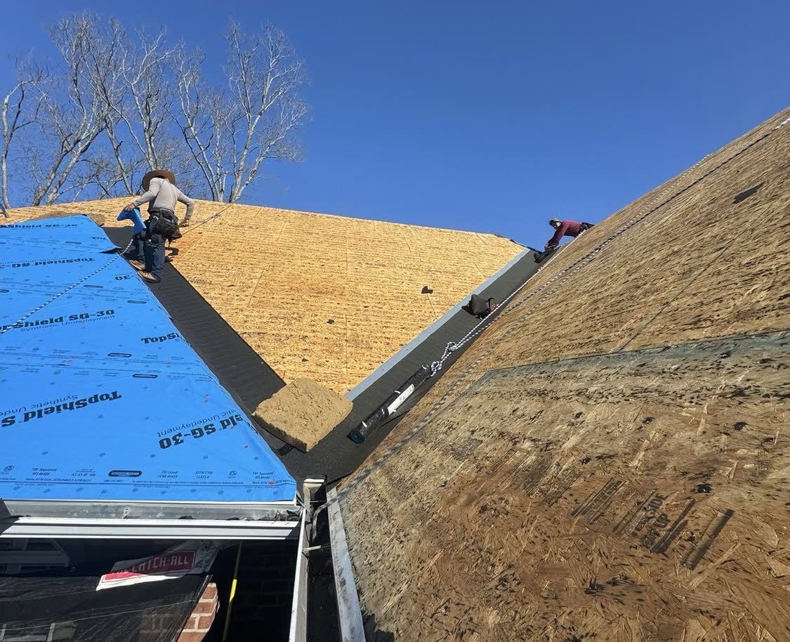 Crew working on exposed roof sheathing during tear-off