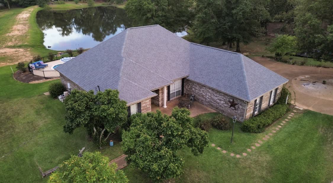 Stone home overlooking a pond with finished gray roof