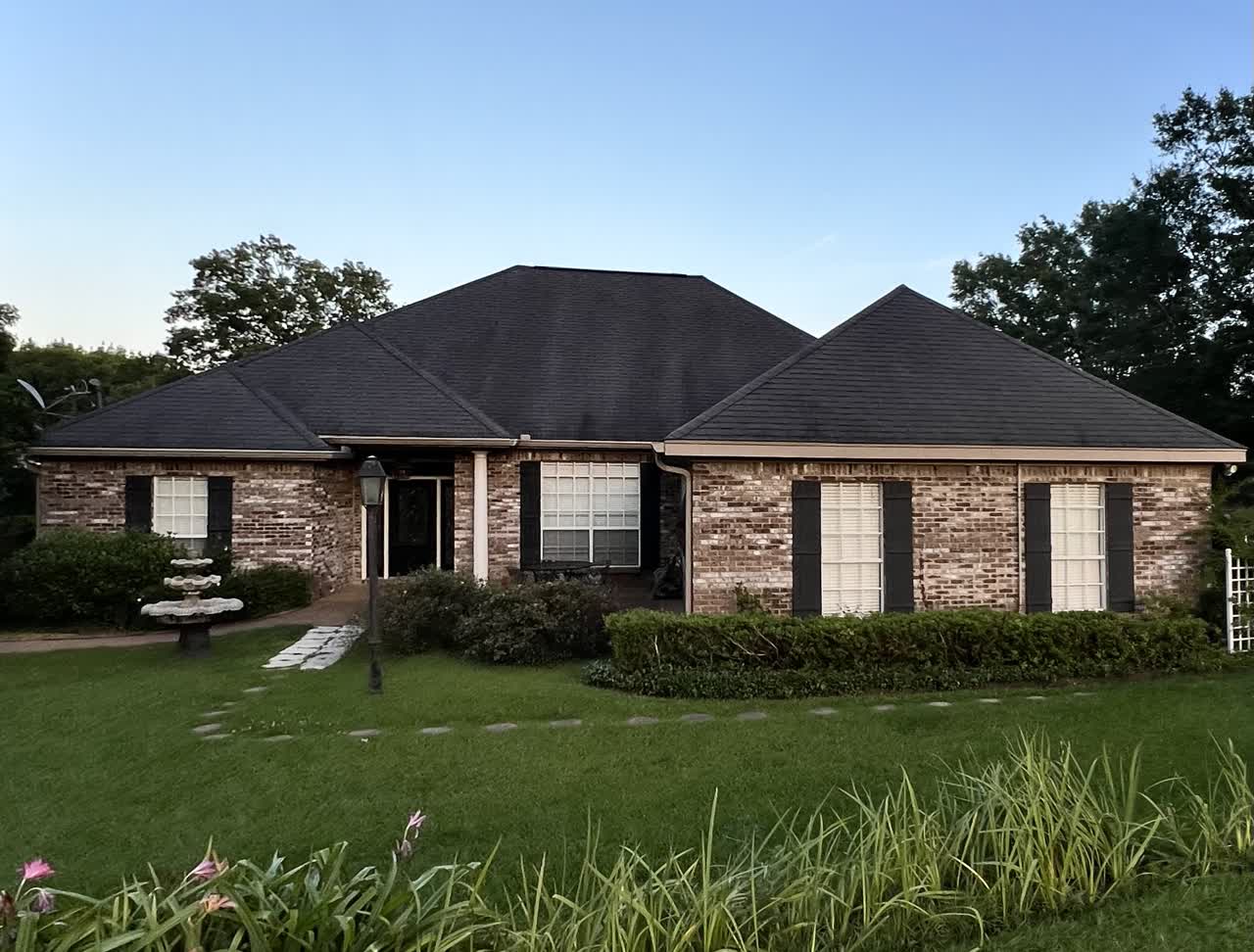 Brick home at twilight with finished dark shingle roof